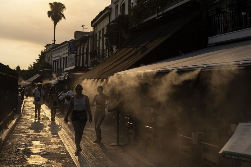 Les gens marchent à côté d'une machine à brouillard pour se rafraîchir, dans le quartier de Monastiraki à Athènes.