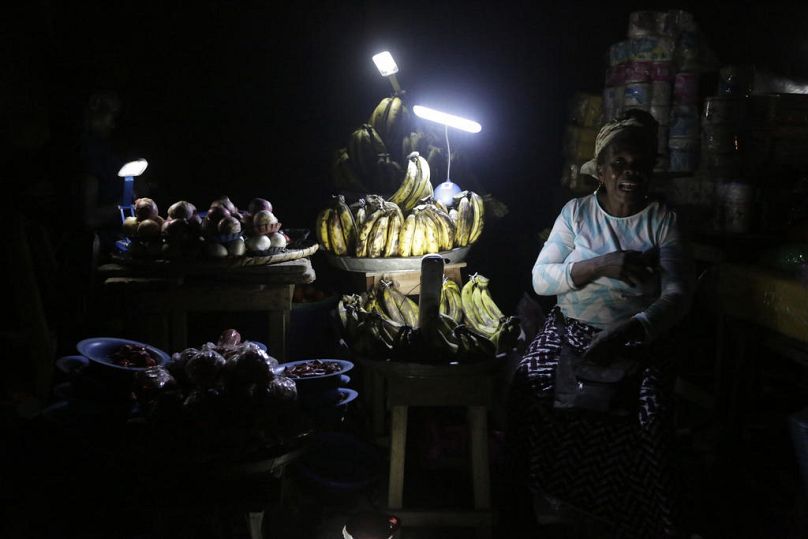 Des vendeurs de légumes présentent leurs marchandises à la lumière de lanternes fabriquées localement à Lagos, février 2017.