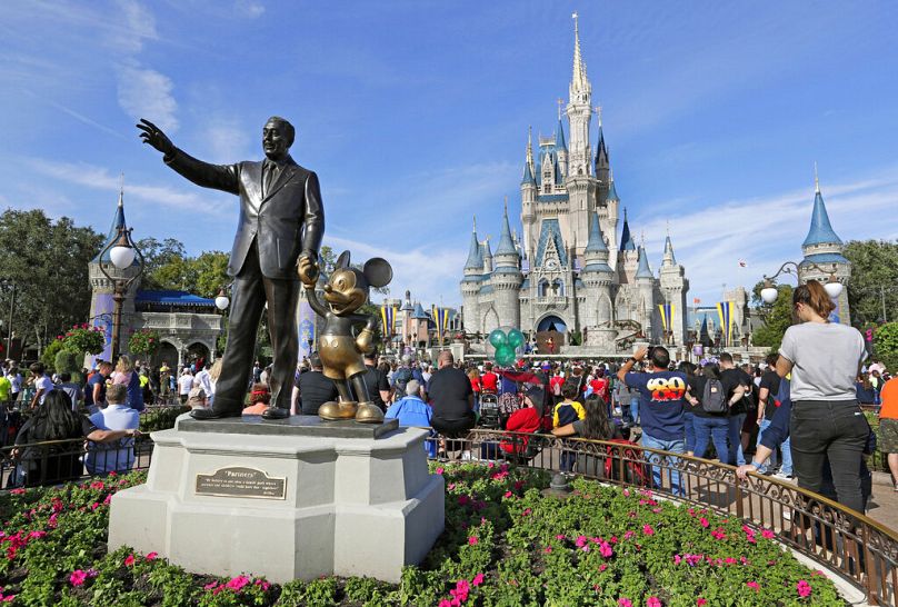 Les invités regardent un spectacle près d'une statue de Walt Disney et Micky Mouse devant le château de Cendrillon au Magic Kingdom de Walt Disney World en Floride.