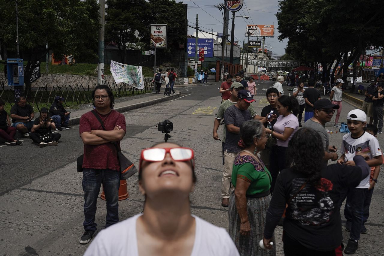 Les gens regardent le « cercle de feu »  éclipse solaire dans une rue bloquée par des manifestants à Guatemala City.