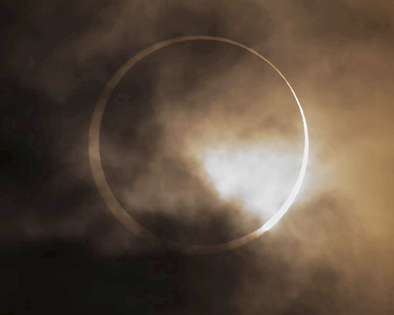 L’éclipse solaire annulaire apparaît derrière les nuages ​​au-dessus de Skinner Butte à Eugene, Oregon, États-Unis, le samedi 14 octobre 2023.