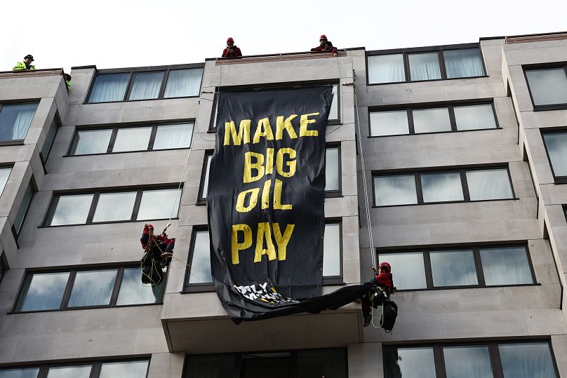 Des militants de Greenpeace déploient une banderole sur laquelle on peut lire « Faites payer les grandes sociétés pétrolières »  depuis le toit de l'InterContinental London Park Lane pendant le 'Oily Money Out&apos ;  manifestation.