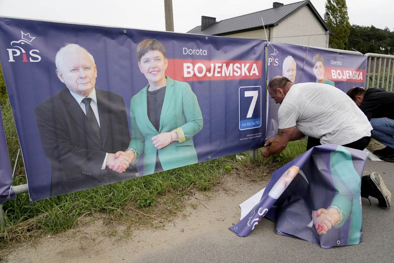 Un homme affiche des banderoles électorales pour un candidat du parti au pouvoir PiS avec le chef du parti Jaroslaw Kaczynski à Czosnow, près de Varsovie, en octobre 2023.