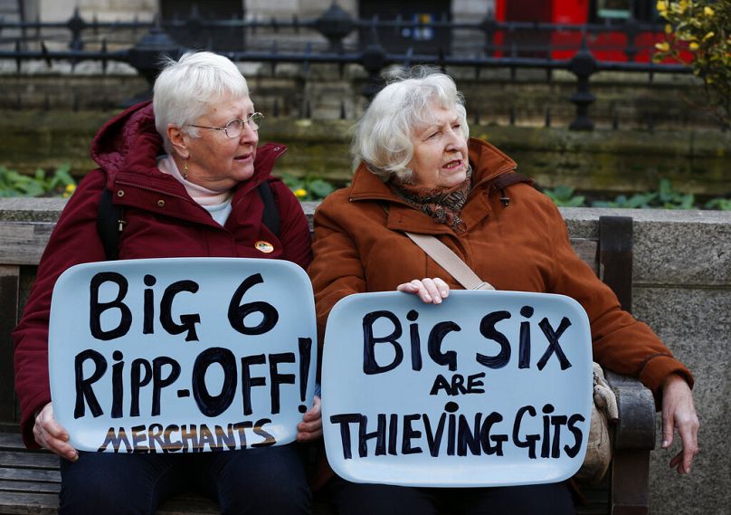 Des manifestants contre la hausse des prix de l'énergie brandissent des pancartes faisant référence aux six fournisseurs d'énergie britanniques, alors qu'ils se rassemblent dans le quartier financier de la City à Londres, en novembre 2013.