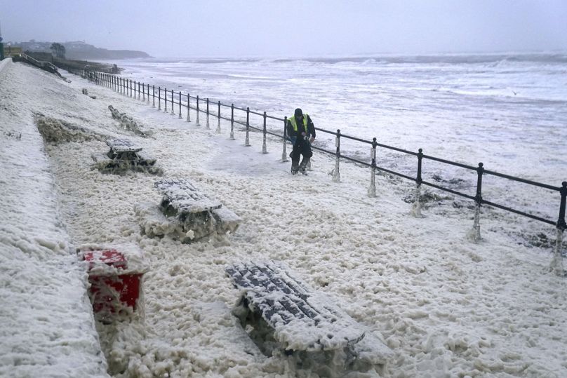 Un homme marche dans l’écume de mer à Seaburn, dans le nord-est de l’Angleterre, le vendredi 20 octobre 2023.