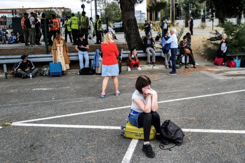 Des passagers attendent devant l'aéroport de Toulouse-Blagnac à Blagnac, dans le sud-ouest de la France, le 18 octobre 2023, après l'évacuation de l'aéroport.