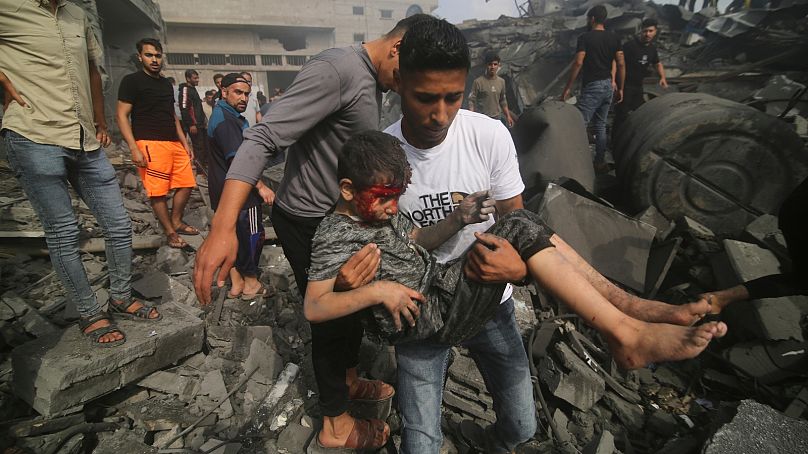 Un Palestinien porte un enfant sorti d'un bâtiment touché lors du bombardement israélien sur la bande de Gaza à Rafah, le dimanche 22 octobre 2023.