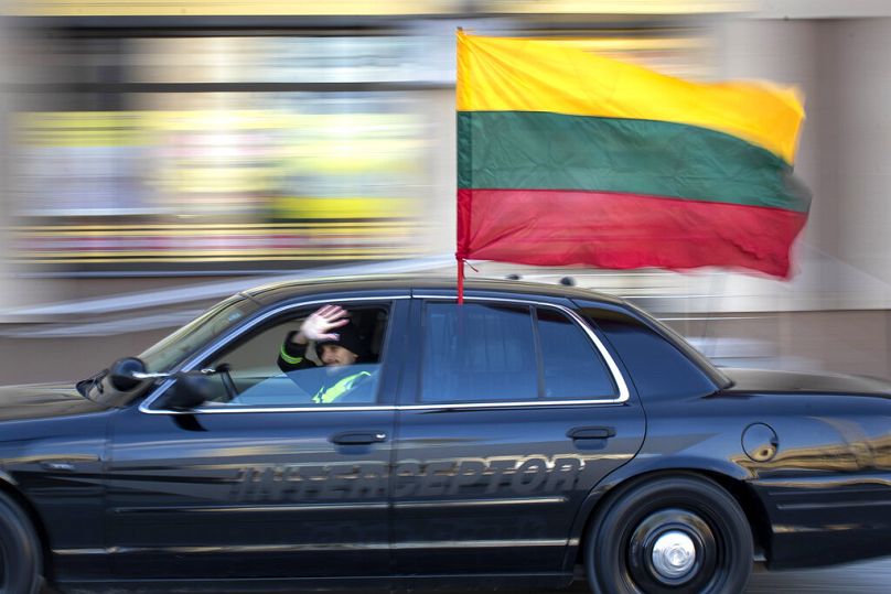 Une voiture arborant un drapeau national lituanien roule le long de l'avenue Gediminas lors d'une célébration du jour de l'indépendance à Vilnius, en Lituanie, le jeudi 11 mars 2021.