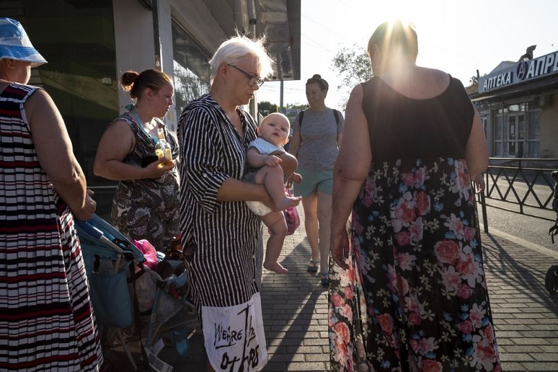 Une femme tient un bébé dans ses bras alors qu'elle marche dans une rue de la station balnéaire de Sotchi, sur la mer Noire, en Russie, le vendredi 15 septembre 2023.