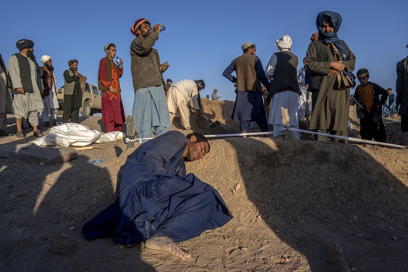 Un Afghan pose sa tête sur la tombe de sa femme décédée à cause du tremblement de terre dans le district de Zenda Jan