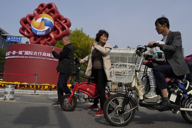 Des résidents passent devant le logo du Forum de la Ceinture et de la Route devant le Centre national des congrès de Chine à Pékin, en octobre 2023.