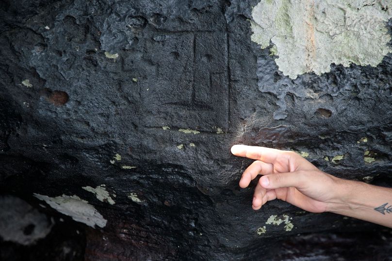 L'archéologue Jaime de Santana Oliveira montre une ancienne sculpture en pierre, exposée après que le niveau de l'eau ait atteint un niveau record lors de la sécheresse à Manaus, le 23 octobre.