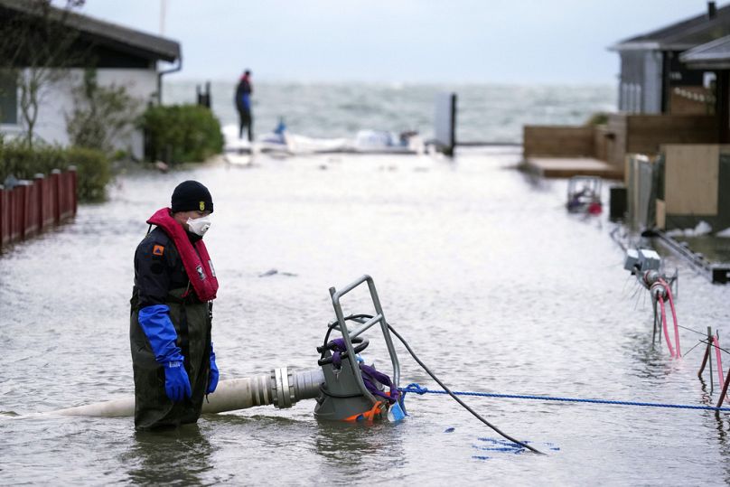 Un ouvrier tente de pomper l'eau de son quartier à Haderslev, au Danemark, le vendredi 20 octobre 2023.