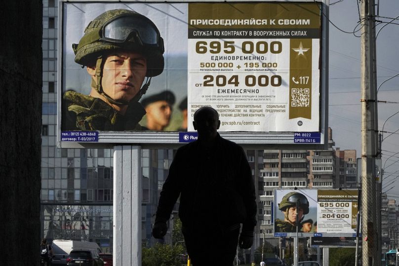 Un homme passe devant des panneaux publicitaires faisant la promotion du service militaire contractuel dans l'armée russe à Saint-Pétersbourg, en septembre 2023.