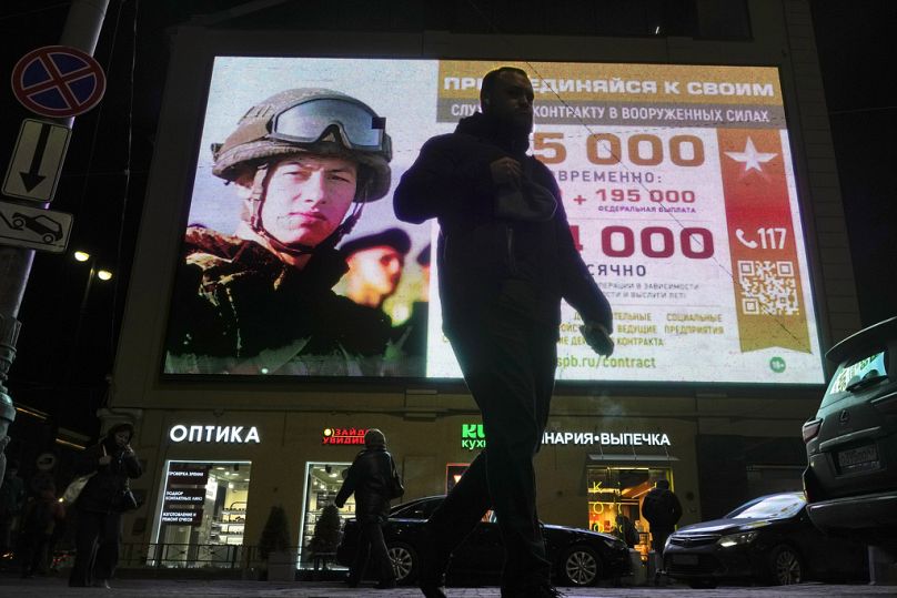 Un homme passe devant un écran publicitaire représentant des soldats de l’armée russe et faisant la promotion du service militaire sous contrat dans l’armée russe à Saint-Pétersbourg, en octobre 2023.
