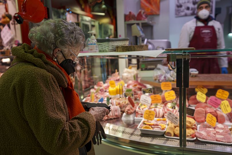 Une femme âgée achète de la nourriture sur un marché de Florence, en Italie, le jeudi 17 février 2022.