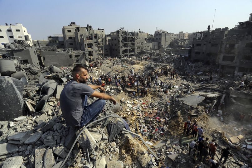 Un homme est assis sur les décombres tandis que d'autres errent parmi les débris des bâtiments visés par les frappes aériennes israéliennes dans le camp de réfugiés de Jabaliya, au nord de la bande de Gaza, mercredi 1er novembre.