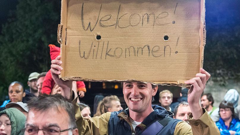 Un homme tient un carton avec le slogan « Bienvenue » lors de l'arrivée des réfugiés à la gare de Saalfeld, dans le centre de l'Allemagne, en 2015.