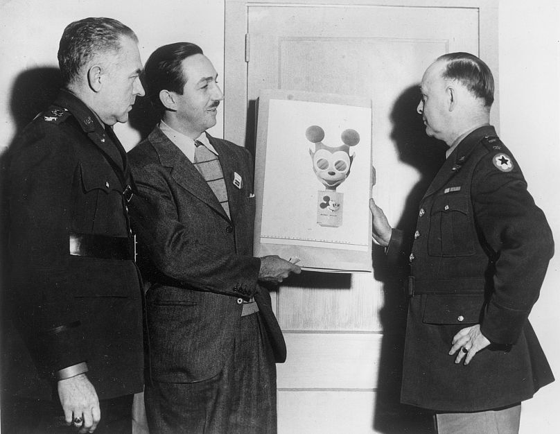 Walt Disney, deuxième à gauche, remet son croquis d'un masque à gaz Mickey Mouse au major général William Porter, à droite, à Washington, DC, le 8 janvier 1942.