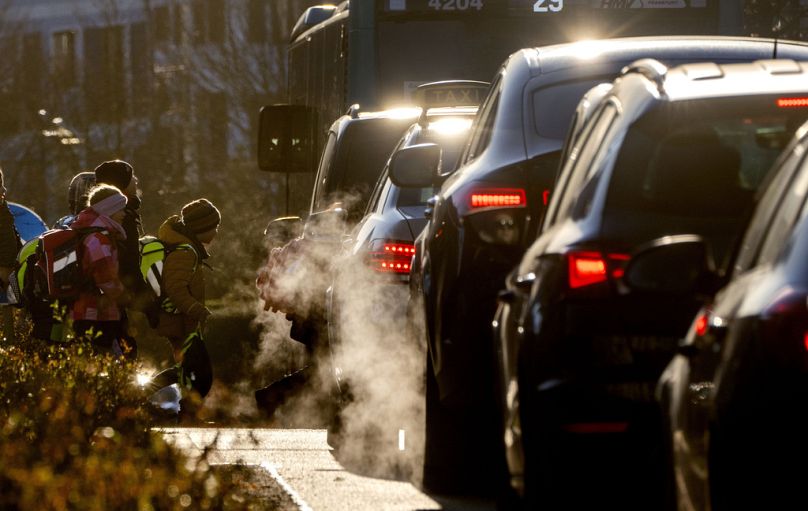 Des voitures dégagent des gaz d'échappement alors que les enfants se rendent à l'école à Francfort, en février 2023.