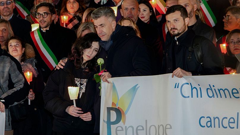 Gino Cecchettin, serrant sa fille Elena dans ses bras, assiste à une procession aux flambeaux à Vigonovo, près de Venise, dans le nord de l'Italie, le dimanche 19 novembre 2023.