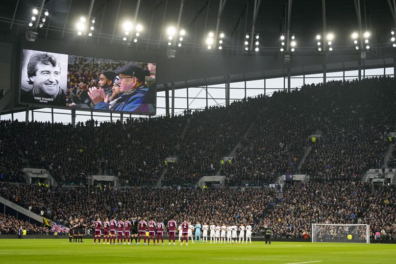 Les joueurs et les supporters applaudissent lors d'un hommage à l'ancien joueur et entraîneur anglais Terry Venables, montré sur l'écran vidéo, avant un match Tottenham-vs-Aston Villa dimanche.