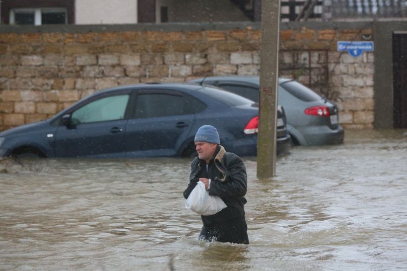 Un homme marche dans une rue inondée lors de l'évacuation des habitants du village de Pribrejnoe en Crimée le 27 novembre 2023, à la suite d'une tempête.