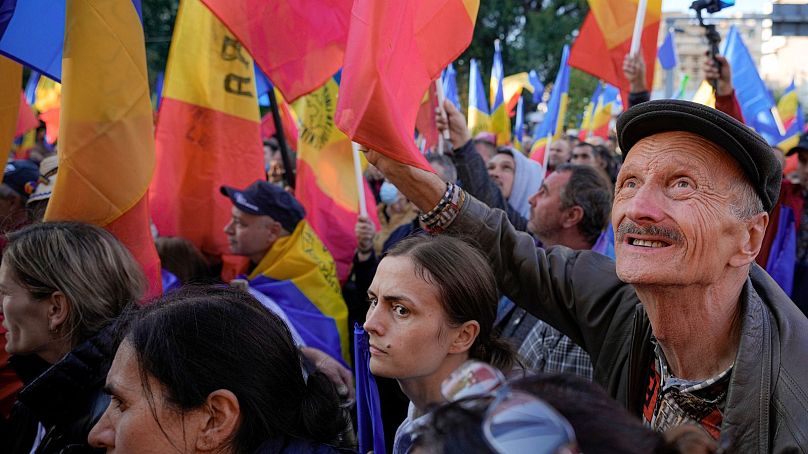 Des gens brandissent des drapeaux lors d'une manifestation antigouvernementale organisée par l'Alliance d'extrême droite pour l'unité des Roumains ou AUR, à Bucarest, en Roumanie, le samedi 2 octobre 2021.