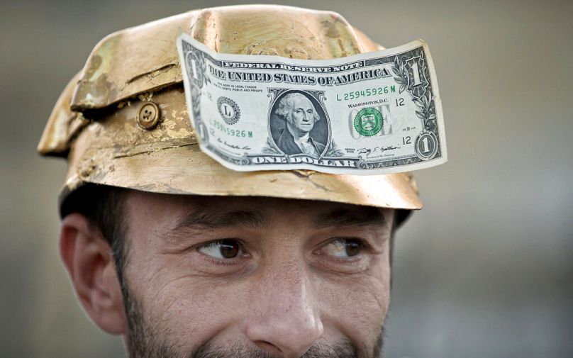 Un homme porte un billet d'un dollar sur un casque de mineur peint de couleur or lors d'une manifestation à Bucarest, en septembre 2021.