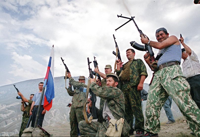 Les troupes du ministère russe de l'Intérieur et les volontaires du Daghestan tirent alors qu'ils célèbrent sur une montagne du village de Tando, août 1999.