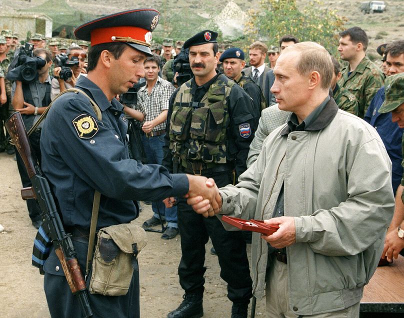 Le Premier ministre russe Vladimir Poutine, à droite, remet un prix à un officier de police local dans une base militaire russe dans les montagnes de la région de Botlikh, août 1999.