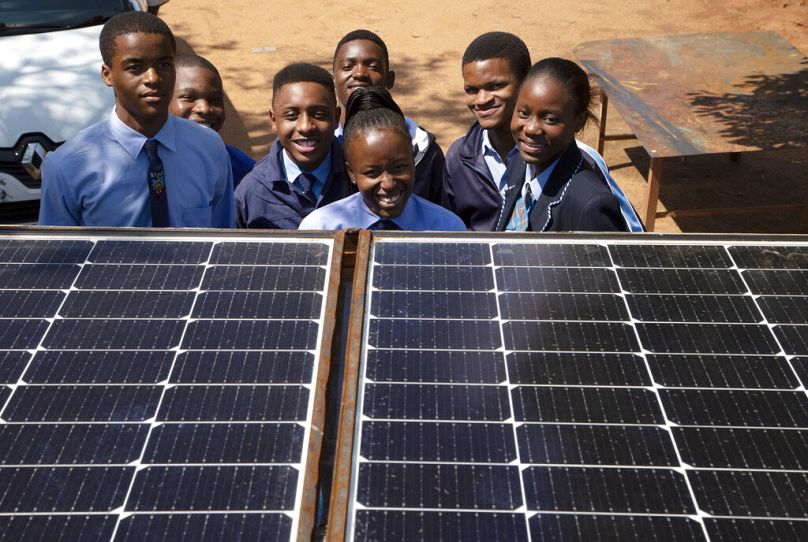 Des étudiants de l'école de spécialisation automobile de Soshanguve posent pour une photo derrière des panneaux solaires sur le toit d'un train, au nord de Pretoria, novembre 2022.