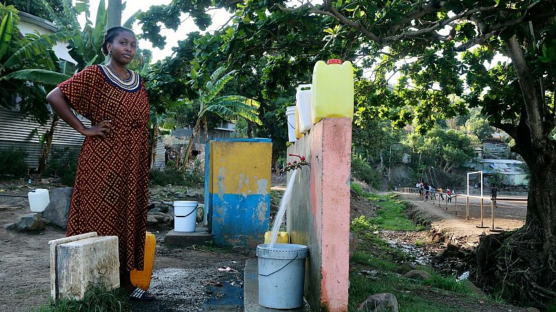 Une femme attend que son seau soit plein à un point d'eau à M'tsamoudou, près de Bandrele, sur le territoire français de Mayotte, dans l'océan Indien, le 21 octobre 2023.