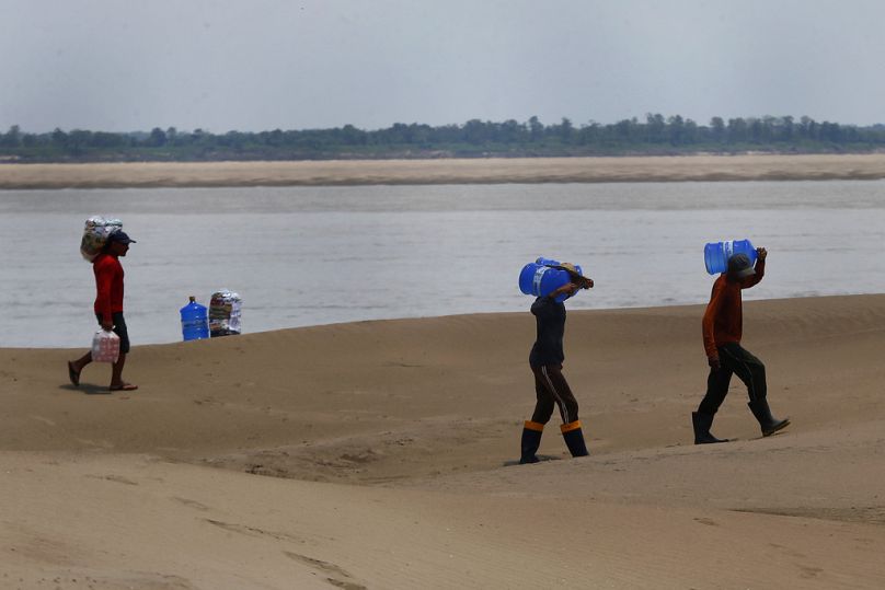 Les habitants d'une communauté riveraine de l'État d'Amazonas transportent de la nourriture et des récipients d'eau potable distribués en raison de la sécheresse et des températures élevées.