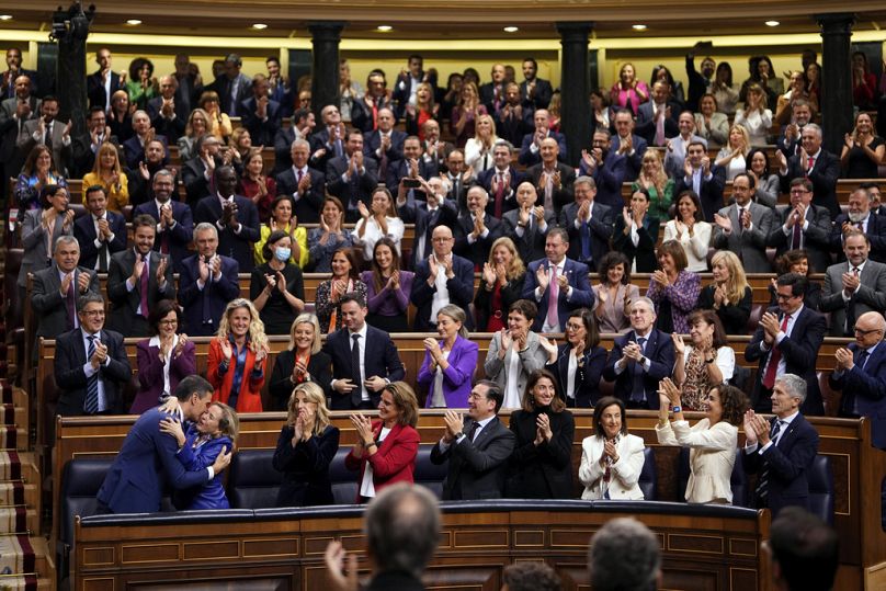 Le Premier ministre espagnol réélu Pedro Sanchez, en bas à gauche, embrasse la ministre de l'Économie et première vice-Première ministre Nadia Calvino au Parlement espagnol à Madrid, en Espagne.