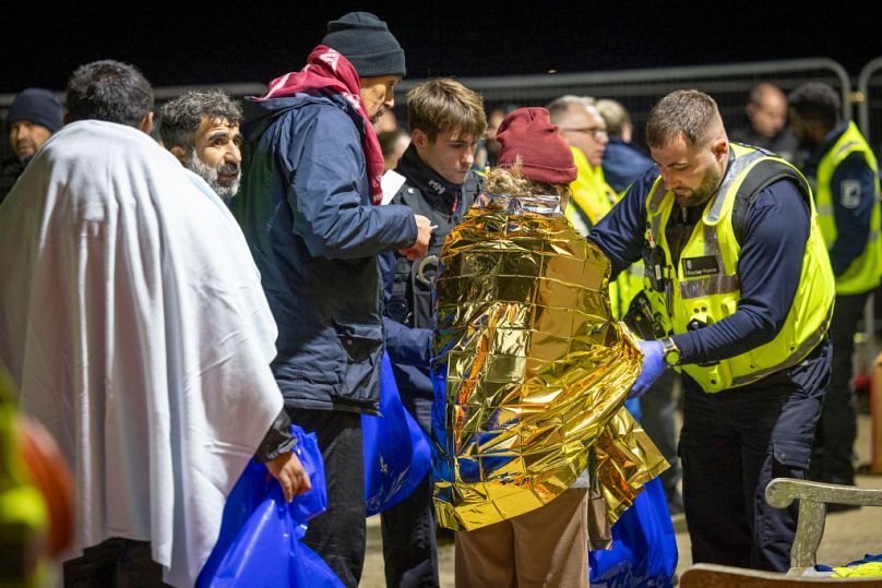 La Garde côtière, le personnel des ambulances, les forces frontalières et la police escortent les demandeurs d'asile qui viennent d'atterrir sur la plage de Dungeness sur un canot de sauvetage de la RNLI.