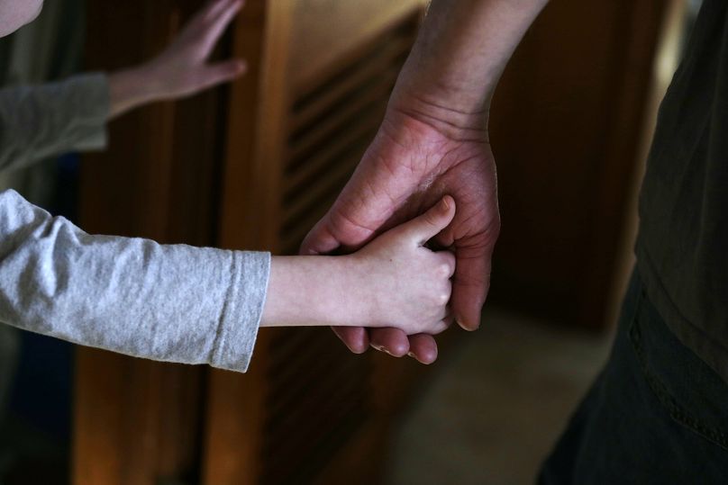 Un garçon autiste tient la main de son père adoptif.