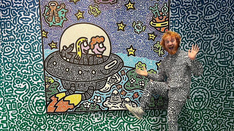 L'artiste britannique Sam Cox, mieux connu sous le nom de Mr. Doodle, pose pour une photo avec son œuvre 