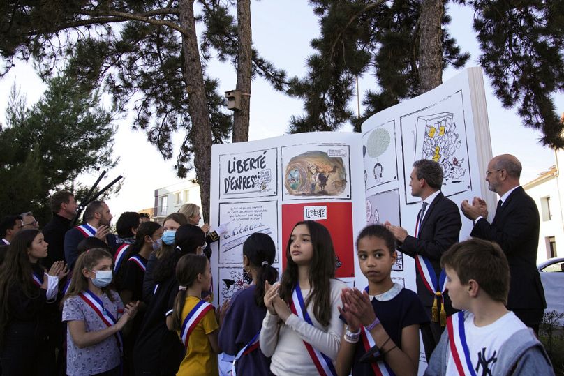 Les enfants dévoilent un livre-sculpture dans le cadre d'une cérémonie d'hommage à Samuel Paty, professeur d'histoire et de géographie française.