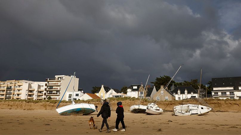 Un couple promène son chien sur des bateaux échoués sur la plage de Pornichet, en Bretagne, le jeudi 2 novembre 2023.