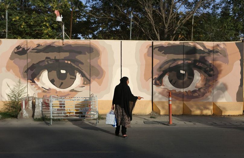 Une Afghane attend son moyen de transport devant des œuvres d'art de rue sur une barrière de la NDS (Direction nationale de la sécurité) à Kaboul, août 2015.