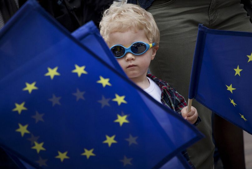 de jeunes garçons brandissent un drapeau de l’UE lors d’un festival devant le Parlement européen à Bruxelles, en mai 2019