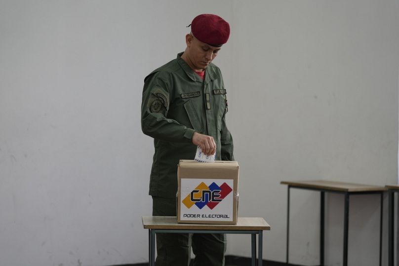 Un soldat dépose son reçu de vote électronique dans une urne lors d'un référendum sur l'avenir d'un territoire contesté avec la Guyane, dans un bureau de vote à Caracas.