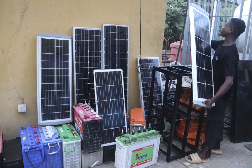 Un homme expose des panneaux solaires à vendre devant un magasin à Abuja, juin 2023