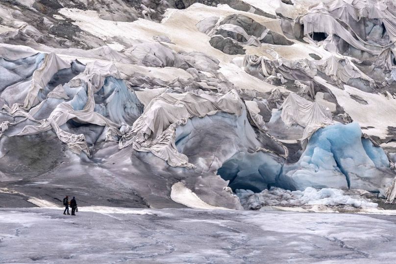 Les membres de l'équipe de l'ETH arrivent au glacier du Rhône partiellement couvert près de Conches, en Suisse, juin 2023