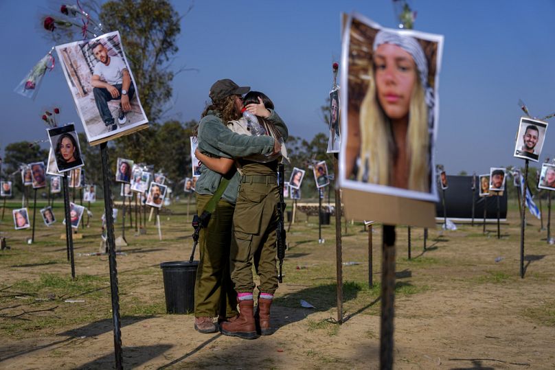 Des soldats israéliens s'embrassent à côté de photos de personnes tuées et capturées par des militants du Hamas sur le site du festival de musique Nova, dans le sud d'Israël, décembre 2023.