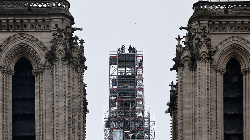 Macron (au centre) visite les travaux de reconstruction et la croix au sommet de la flèche nouvellement reconstruite, à la cathédrale Notre-Dame de Paris.