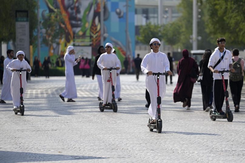 Des gens conduisent un scooter électrique lors du Sommet des Nations Unies sur le climat COP28 à Dubaï, en décembre 2023.