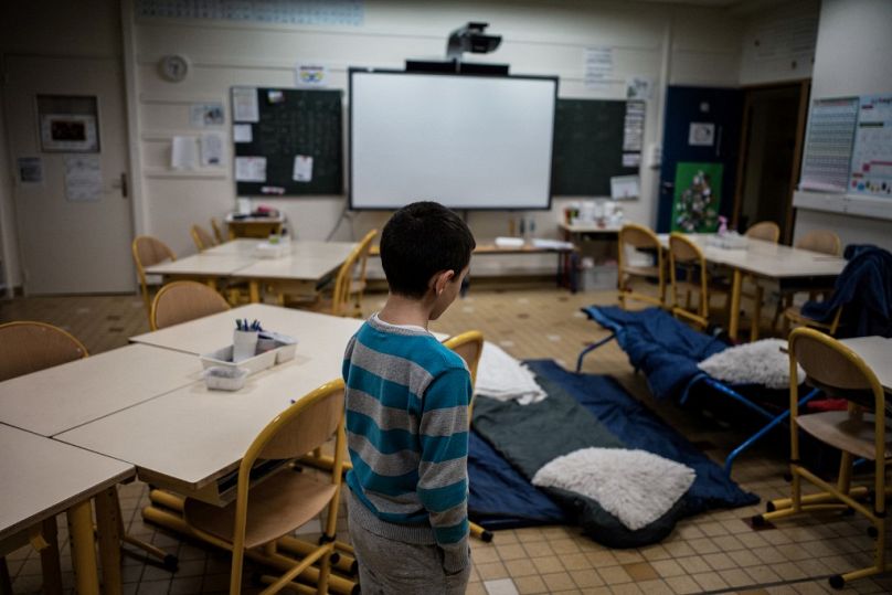 Un enfant se prépare à dormir dans une salle de classe le 10 janvier 2018 à Vaulx-en-Velin, près de Lyon, dans le centre-est de la France.