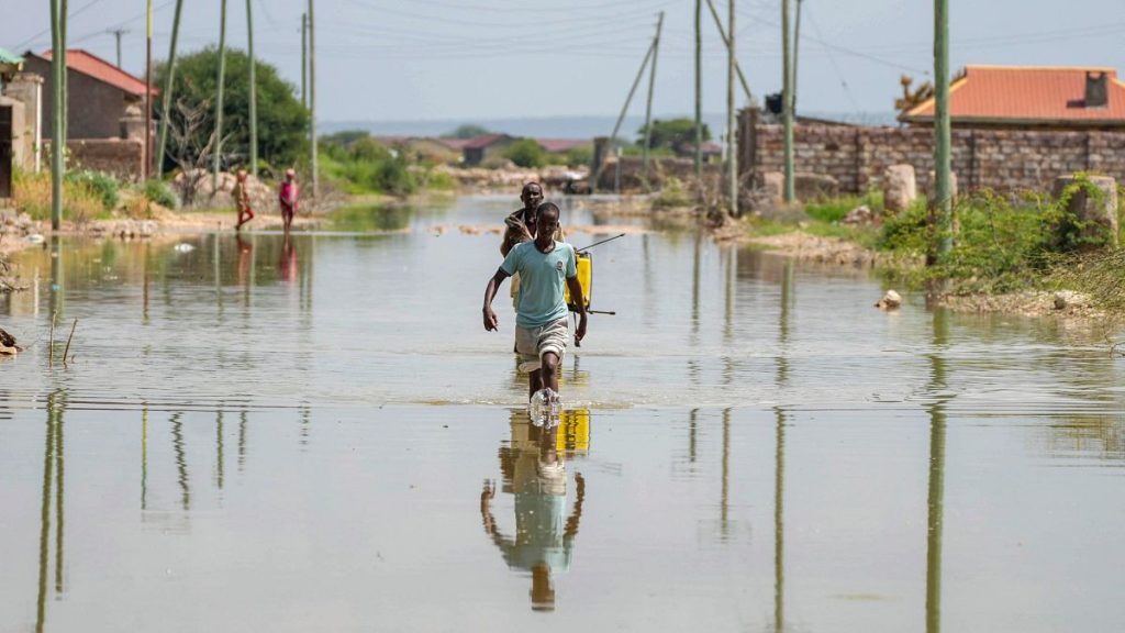 People wade through a section of a road destroyed by floods in Mandera County, Kenya, Wednesday, Dec. 13, 2023.